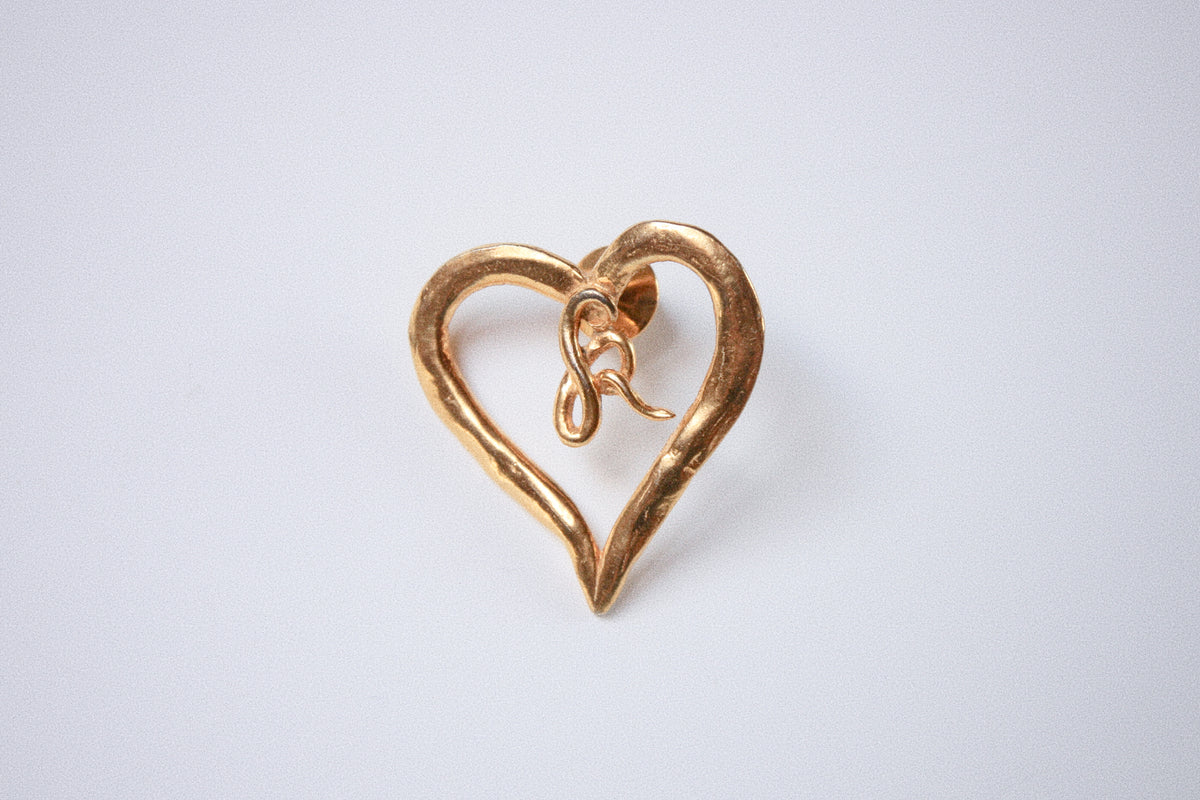 Vintage gold heart-shaped brooch on a neutral background