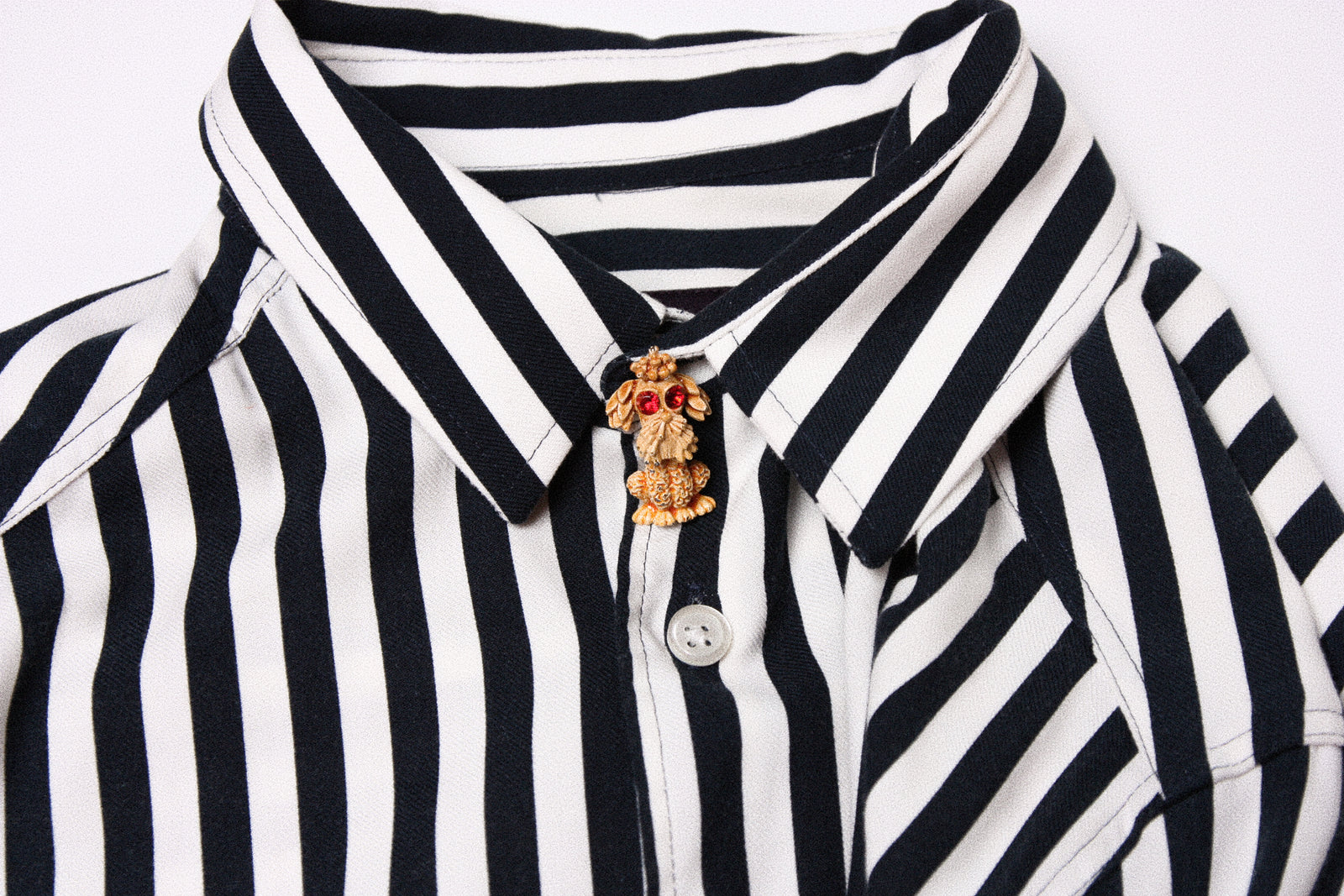Vintage gold David Grau brooch pinned to a striped shirt collar