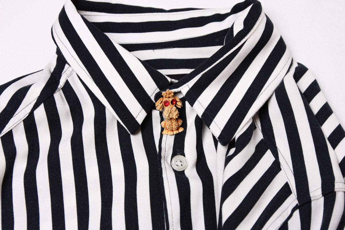 Vintage gold David Grau brooch pinned to a striped shirt collar